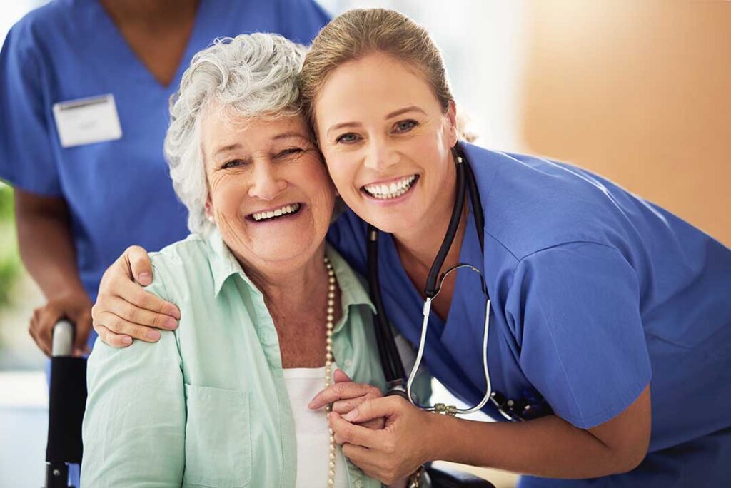 Caregiver respectfully assisting an older resident in a bright, clean assisted living common area.